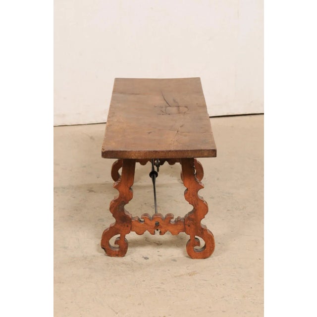 A Spanish wooden coffee table, with lyre legs and iron stretcher, from the turn of the 19th and 20th century. This antique...