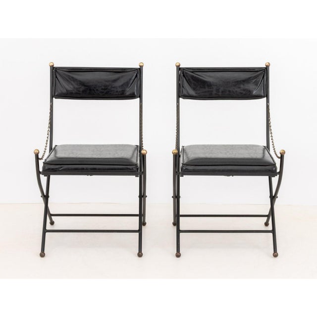 Pair of Maison Jansen Style Campaign Chairs, with faux leather upholstery. 33" H x 19.5" W x 23" D; seat 18" H....