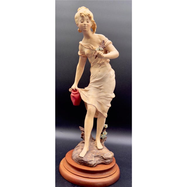 Beautiful Vintage Capodimonte figurine depicting a young lady in a flowing dress holding flowers and a red vase. These...