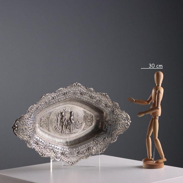 Embossed, openwork, chiseled, and burin-worked silver centerpiece. The rim features a wavy, openwork edge and a floral...