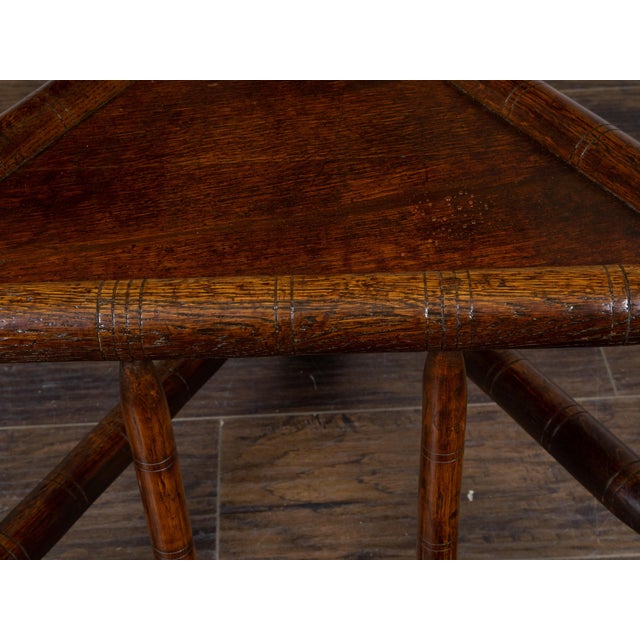 This English Turn of the Century oak corner chair, dating back to circa 1900, features a carved geometric back splat,...