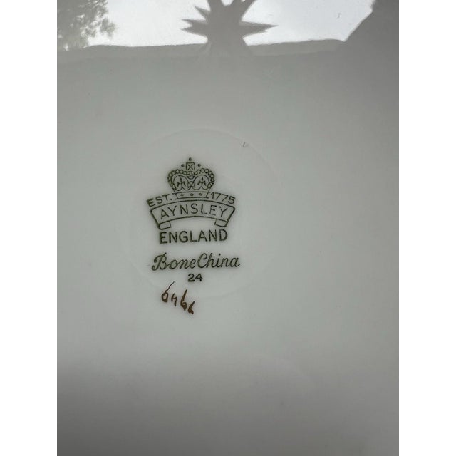 The Vintage Aynsley 7949 Gold Encrusted Dinner Plate is a 10.5/8" round dinner plate made of bone china, featuring a...