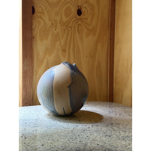 A hand-built spherical studio pottery vase with a distinctive pinched, torn-edge opening at the top rather than a...