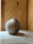 A hand-built spherical studio pottery vase with a distinctive pinched, torn-edge opening at the top rather than a...