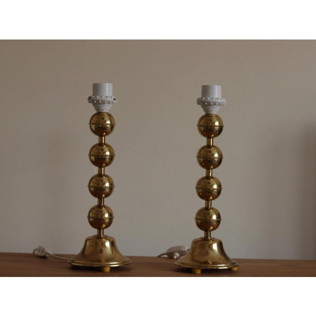 Made in sweden two exquisite swedish polished brass table lamps by aneta featuring a delightful round bobbin-style design,...