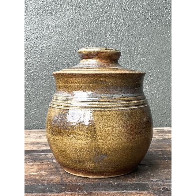 This exquisite hand-thrown studio pottery lidded jar is a masterclass in the organic beauty and tactile expression of late...