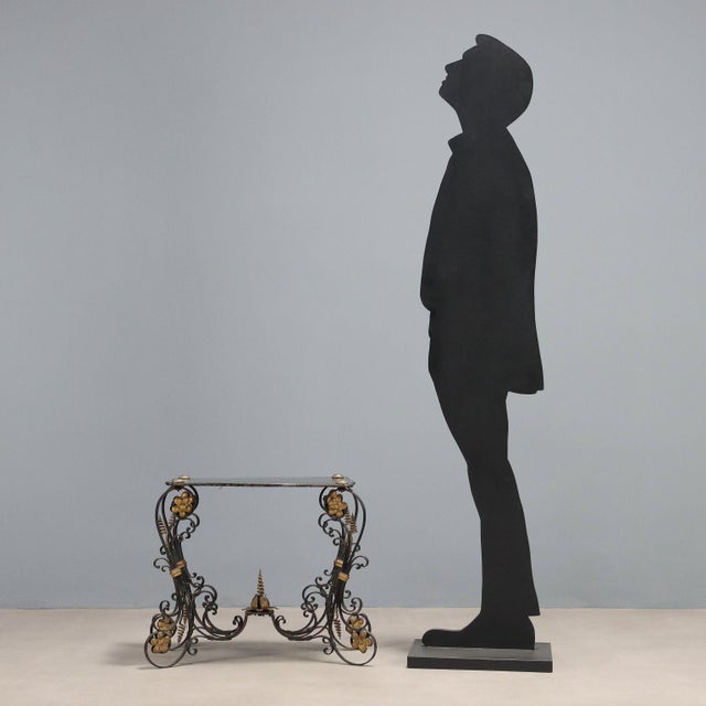 Coffee table. Lacquered wood top supported by four wrought iron legs decorated with scrolls and curls, joined by a...