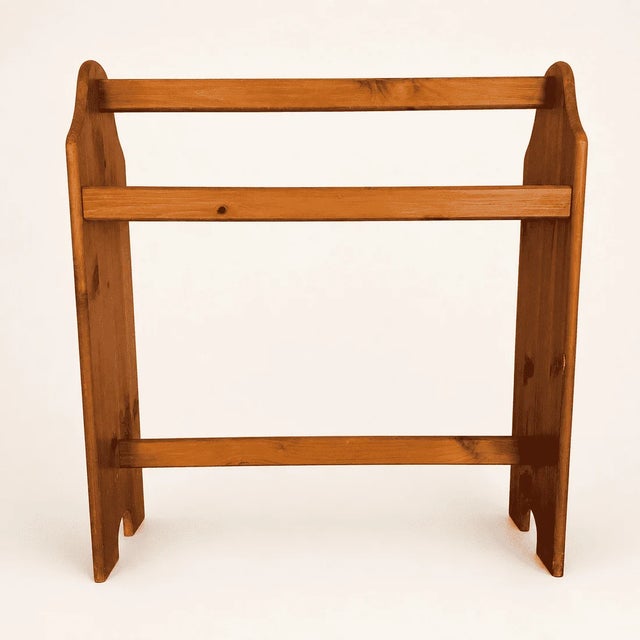 A freestanding pine quilt rack with three rails and gently scalloped side panels on cutout feet. It's the classic country...