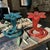 This vintage pair of blue and orange red art glass bud vases features a ruffled flower top and a spiral base, adding a...
