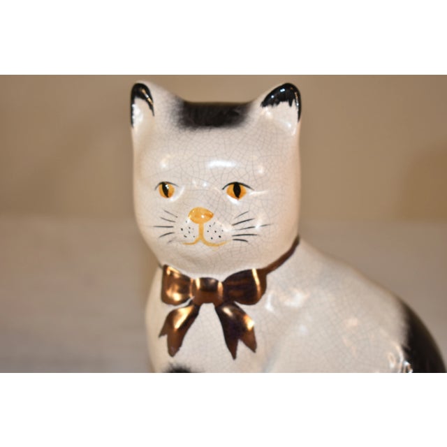 Circa 1970 vintage figure of a cat from the Staffordshire region of England. The cat is decorated in black and white, and...