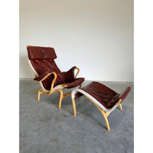 Swedish Mid Century Modern Lounge Chair and Ottoman set designed by Bruno Mathsson for DUX. Deep chocolate brown leather...
