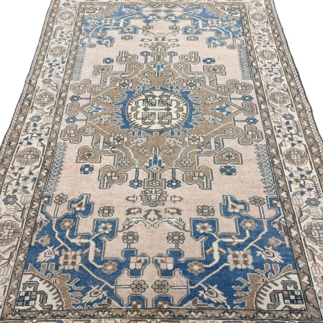 This beautiful vintage rug features a bold and highly stylized central medallion set against an ivory ground. The...