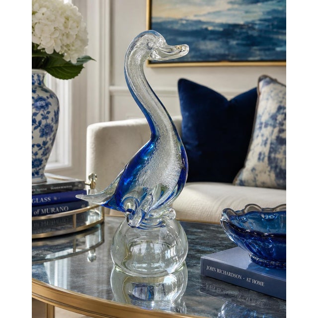 A striking vintage art glass swan sculpture featuring a graceful elongated neck, vibrant cobalt blue accents, and...