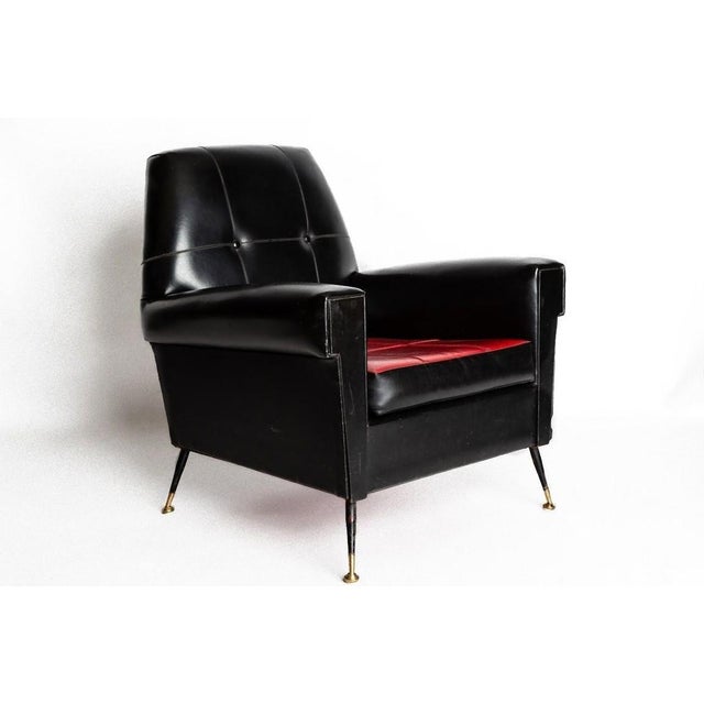 This vintage armchair is a piece of design furniture manufactured in Italy in the 1970s. Made in black leather with brass...