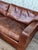 Distressed brown leather sofa has a low-profile design with two large seat and back cushions. This piece is upholstered in...