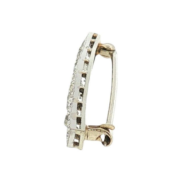 An Edwardian platinum-and-14k gold diamond brooch. This elegant piece features a row of 14 old mine-cut diamonds, totaling...