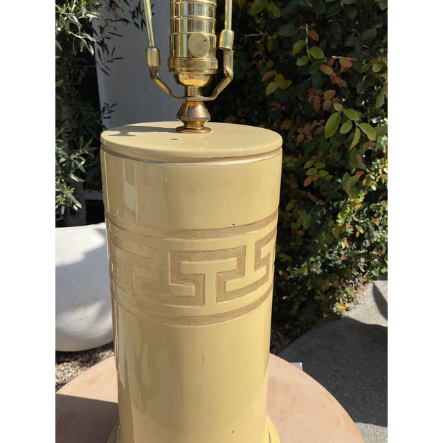 Vintage column-form table lamp featuring a raised Greek key motif band and gold leaf detailing over a warm yellow...