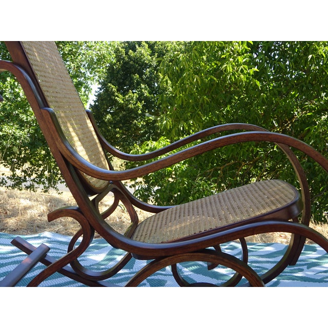 Vintage rocking chair made in the 1980s. Solid wood frame, dark oak-stained beech. Seat and backrest covered in rattan...