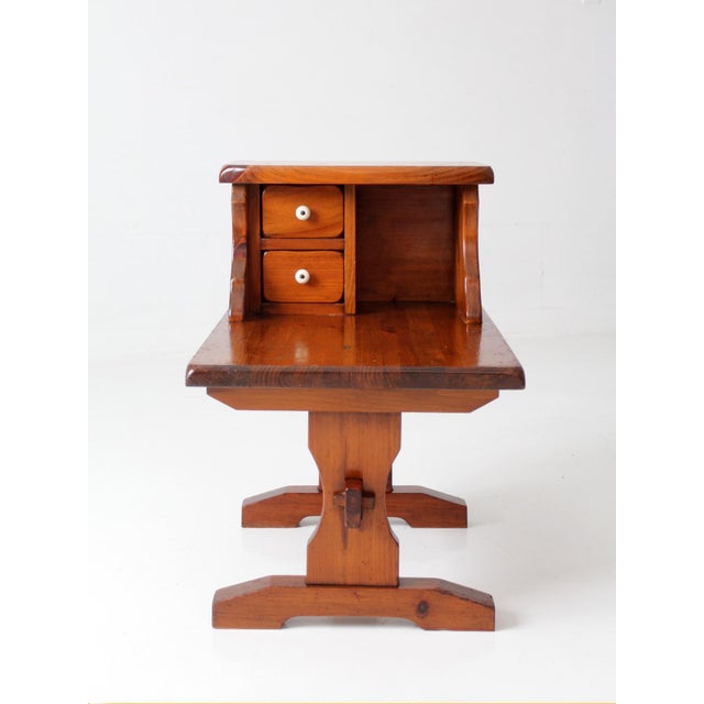 A vintage 1970s pine end table with a charming two-tier design, featuring a raised gallery, two small drawers with white...