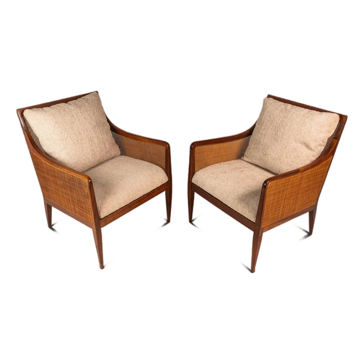 Two walnut mid-century modern caned lounge chairs with light fabric cushions.