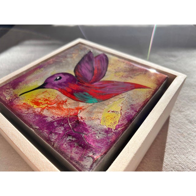 This artwork features a vibrant hummingbird, captured in mid-flight with expressive strokes that emphasize its dynamic...