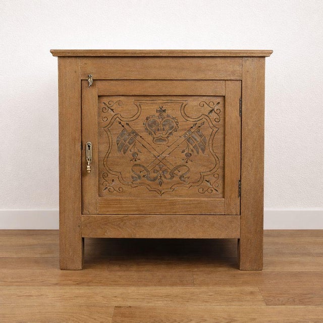 Antique oak side cabinet featuring a door adorned with delicate carved motifs and original brass hardware. Its sturdy...