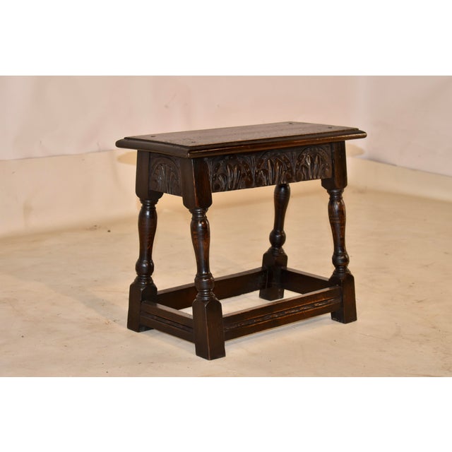Late 19th century oak joint stool from England with hand carved decoration. The top has a beveled edge and pegged...