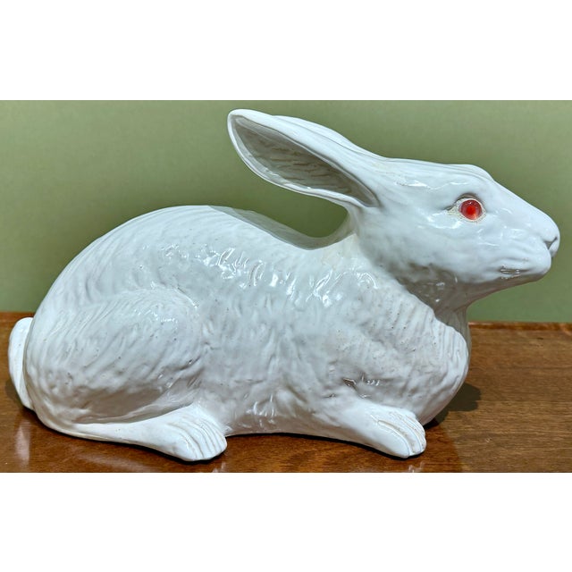 An antique Bavent rabbit figurine in tin glazed terracotta, with a calm, compact pose, subtle texture, and original pink...