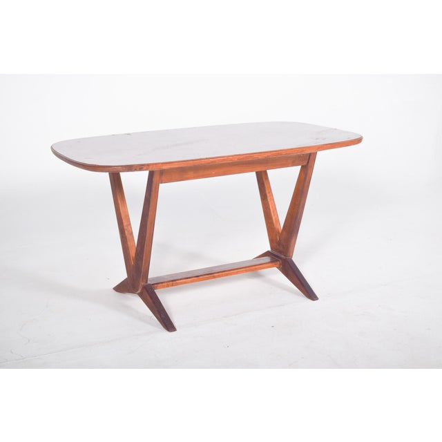 Rectangular coffee table with V-shaped legs. With rounded corners and a light colour, it has a smooth finish and gently...