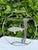 A sculptural metal “fish bowl” featuring a textured fish suspended within an open wire vessel, surrounded by hand-formed...