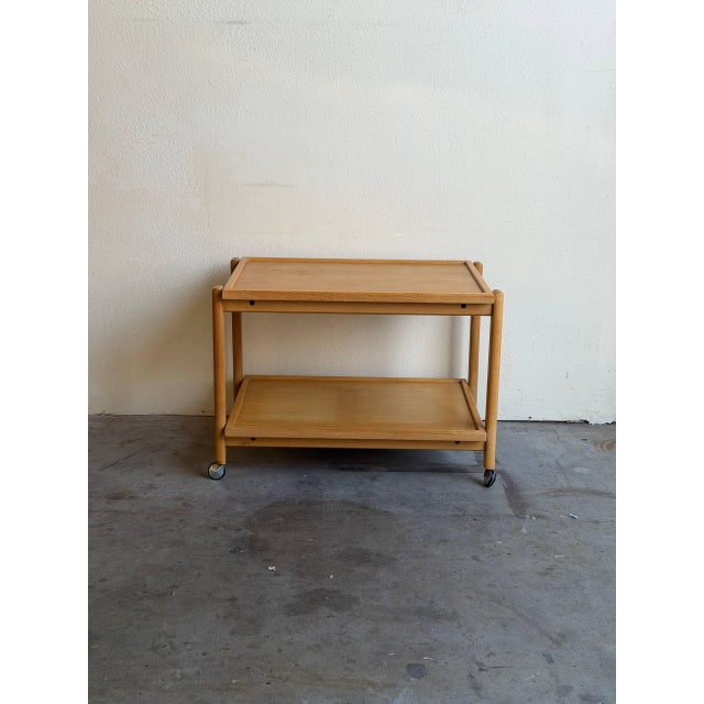 This vintage Danish rolling cart features a timeless Mid-Century Modern design with warm oak tones, clean lines, and...