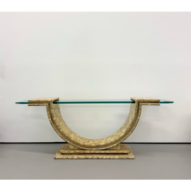 A dramatic vintage console table featuring a sculptural U-shaped base finished in a glossy lacquered faux-stone pattern....