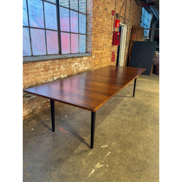 A stunning mid-century modern dining table designed by George Nelson for Herman Miller, featuring a richly figured...