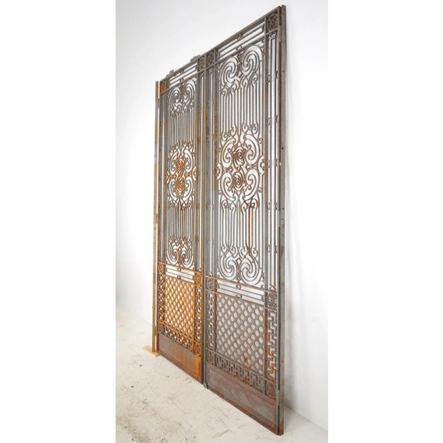 Victorian style double door gates made of wrought iron panels and steel frames. It features intricate filigree scrollwork...