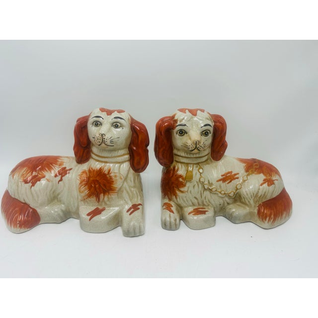 This is a pair of antique staffordshire ceramic dog figurines depicting spaniel-type dogs with long ears, finished in a...