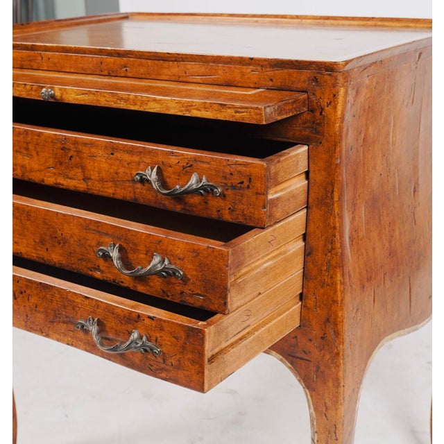 A charming French Provincial style side chest featuring three drawers, a pull-out slide, and an elegant silhouette raised...