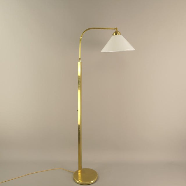 Massive brass floor lamp with opal glass shade the lamp gives a cosy, non-dazzling light. polished surface. the lamp has...