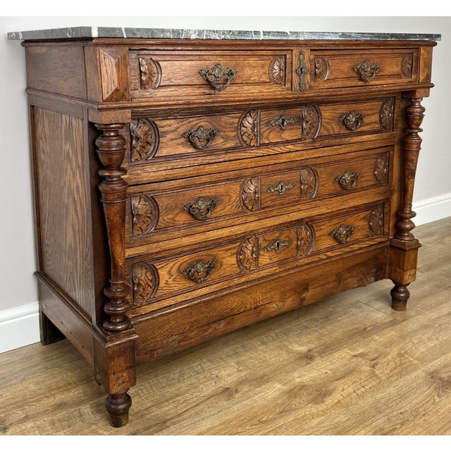An elegant Antique French walnut chest of drawers featuring a striking marble top, beautifully carved drawer fronts and...