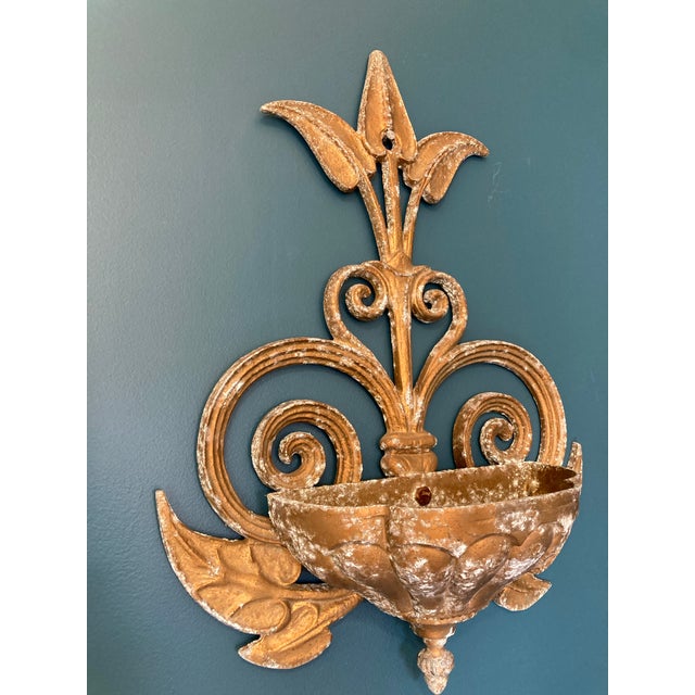 An elegant vintage cast iron wall planter featuring a classic fleur-de-lis crest, ornate scrolling details, and a molded...