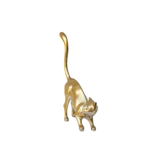 A modernist brass cat in a curious pose, with an unimpressed expression. Cast with fluid lines curved through the tail and...