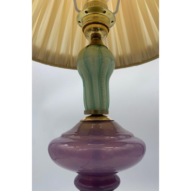 Classic-style table lamp with a truncated cone-shaped lampshade in ivory-colored pleated fabric, embellished with...