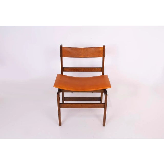 Rationalist style chair, wooden structure, seat upholstered again in leather and backrest with its original leather. Of...