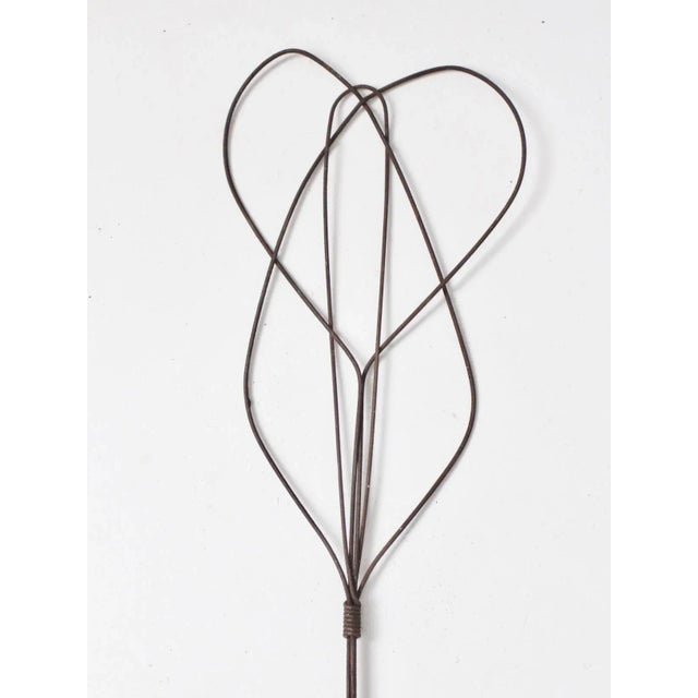 This is an antique rug beater. The carpet beater has a honey-comb twisted design with wooden handle with metal loop hang.