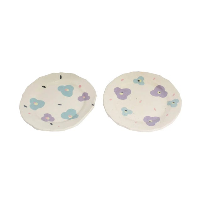 A pair of Postmodern ceramic plates by the American artist Madeline Kaczmarczyk. These two white ceramic plates with...