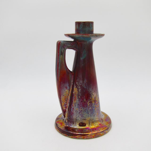 An antique candle holder or chamber stick with one handle decorated in a deep red lustre glaze accented with fiery...