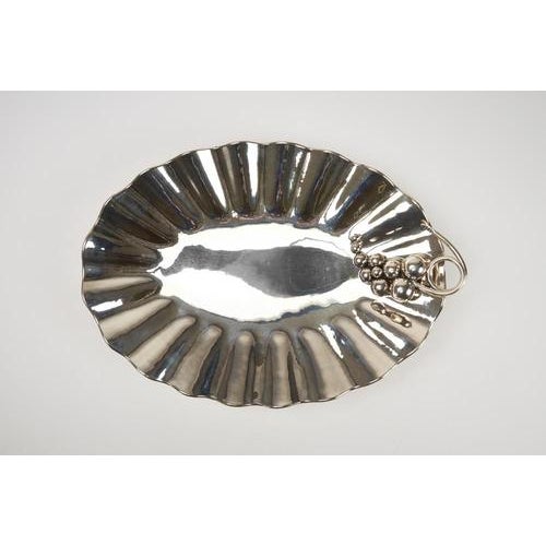 Centerpiece tray crafted from hand-embossed 800-silver sheet metal, featuring a grapevine design on the sides. Made in...