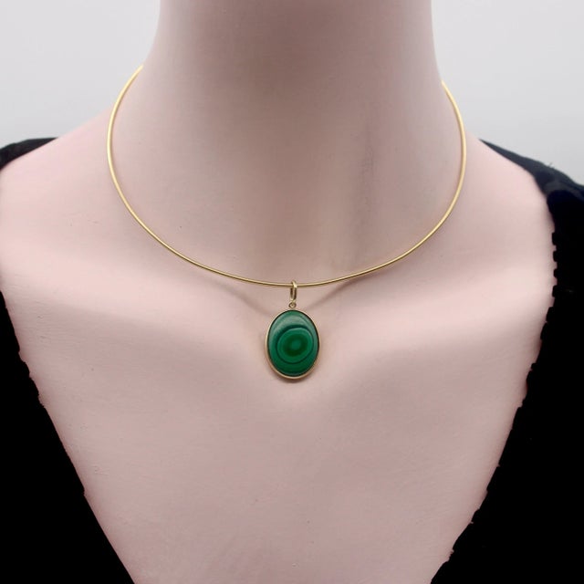 A bezel set malachite in 14k gold creates an oval-shaped pendant. Malachite—a green gemstone known for its beautiful...