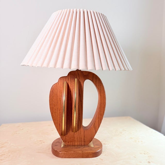 A wonderfully sculptural mid-century table lamp with a carved oak base featuring an open cutout form — organic, shield-...