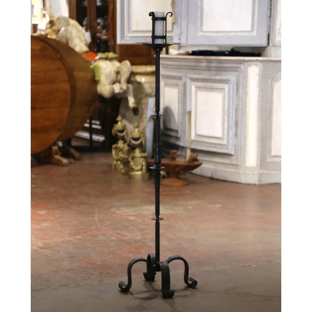Crafted in France circa 1780 and forged of solid iron, the candle holder stands on four scrolled legs over a turned...