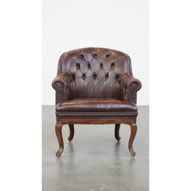 This classic and charming, correctly finished cowhide English chesterfield armchair with graceful legs. This dark cowhide...